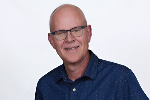 Man in blue shirt with glasses and a white background