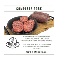 Raw pork patties and sausage on a cutting board with Grand Dog Essentials branding.