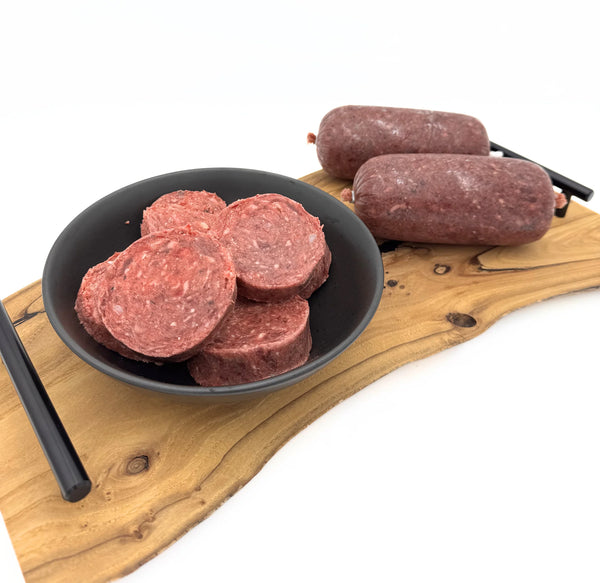 Raw pet food in a bowl and on a wooden board with a white background