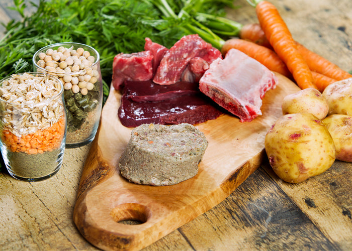 beef raw dog food on a cutting board with potatoes and carrots