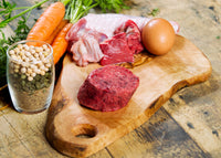Turkey raw dog food on a cutting board with eggs and carrots